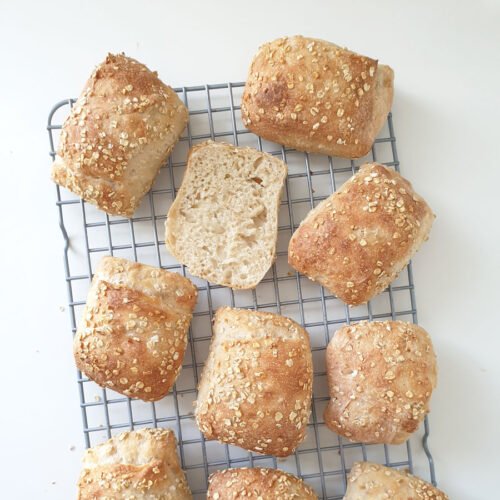 Birdview - baked bread rolls named Oaty's on rack with one cut open showing crumb - made with baking mix from BREADISTA