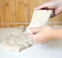 two hands stretch piece of raw bread dough - BREADISTA Almweck mix