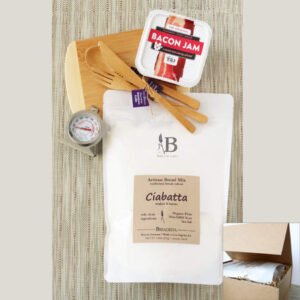 Birdview - Content of Bread Bakers Little Gift box with bamboo cutting board and utensils, bread mix in white pouch, oven thermometer, jam