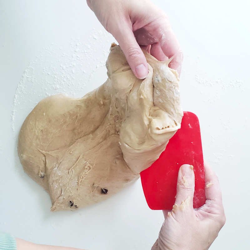 Birdview - two hands lift sticky Colomba dough on one side ready to be fold