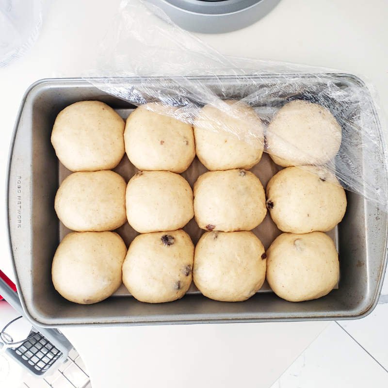 Birdview - 12x raw and proofen dough balls in baking pan partially covered with foil