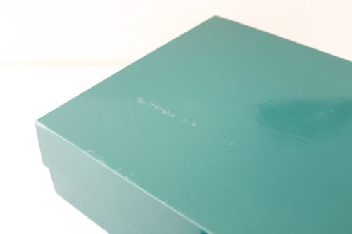 surface with abrasions on lid of green glossy gift box