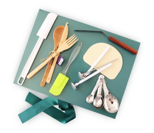 birdview: green glossy gift box with satin ribbon on side, on top lay different kitchen baking tools spread out - Clearance picture