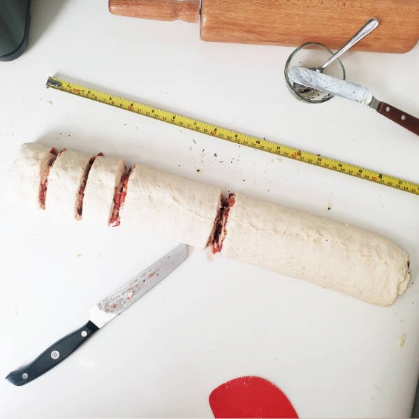 rolled up dough gets cut into pieces for pizza rolls - BREADISTA
