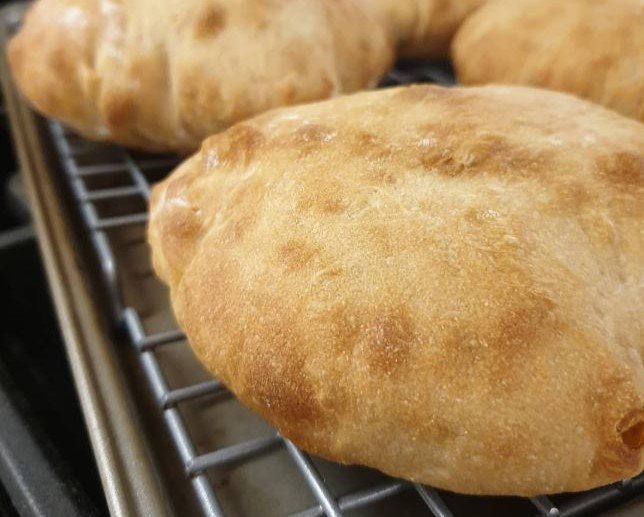 baked pita pockets on cooling rack - close up - by BREADISTA