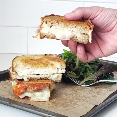 grilled cheese sandwiche halves, stacked and one hold with a hand by BREADISTA