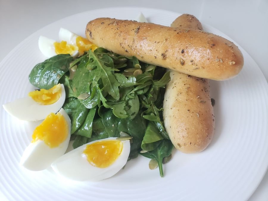 baked homemade Breadsticks on green salad with hard boiled cut open egg quarters - BBREADISTA, serving suggestion