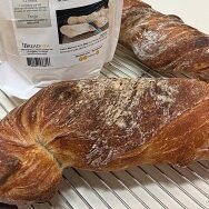 Review - Wurzelbrot: two baked and twisted baguette loaves on rack with packaging - BREADISTA artisan bread mix