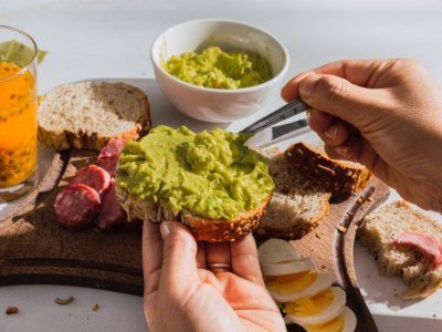 hand smears guacamole on bread - Wurzelbrot BREADISTA - Lifestyle - close up